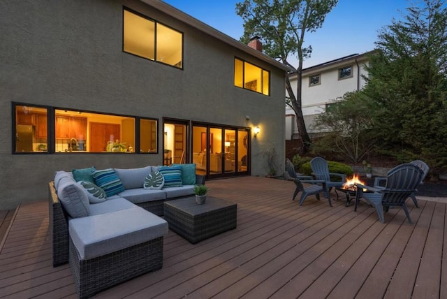 deck at dusk featuring an outdoor living space with a fire pit