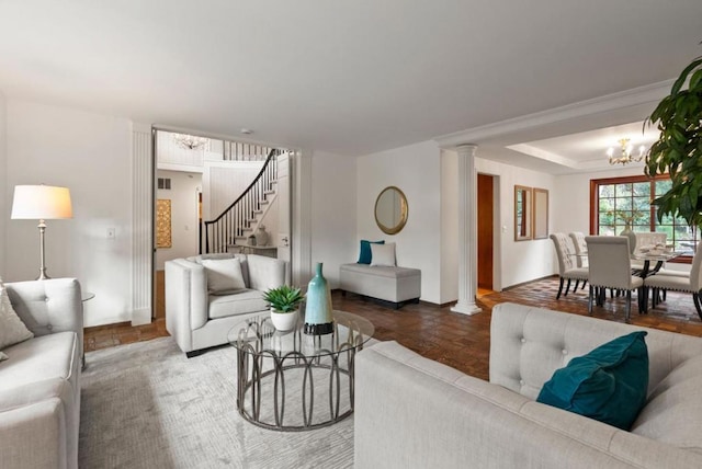 living room featuring an inviting chandelier, decorative columns, and a raised ceiling