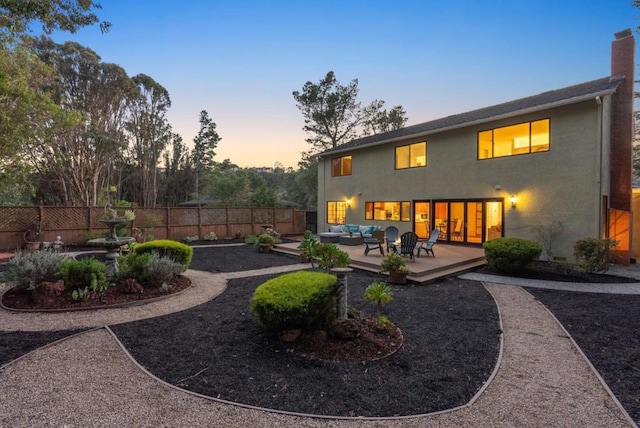 back house at dusk with an outdoor living space and a patio area