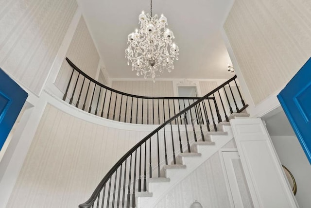 stairs with an inviting chandelier and a towering ceiling