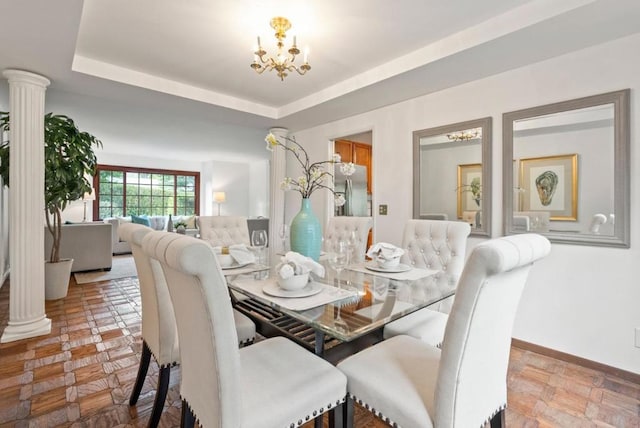 dining room featuring decorative columns, a raised ceiling, and an inviting chandelier