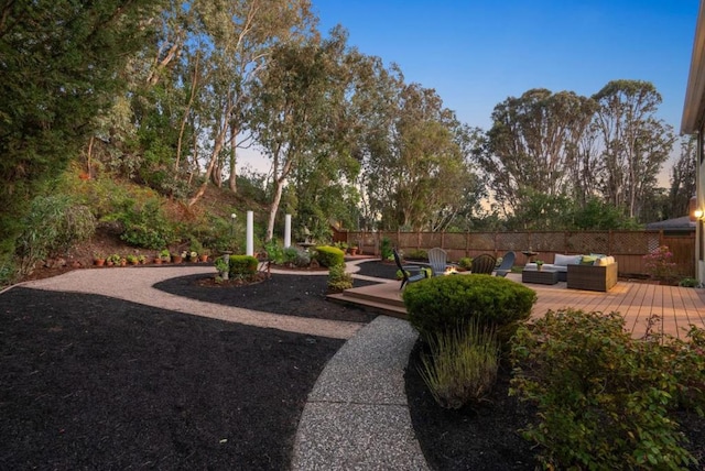 yard at dusk with an outdoor living space and a wooden deck