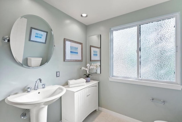 bathroom with toilet, sink, and a wealth of natural light