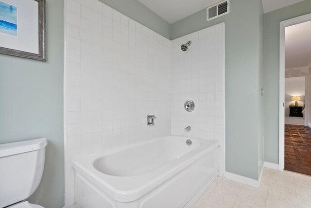 bathroom featuring toilet and tiled shower / bath combo