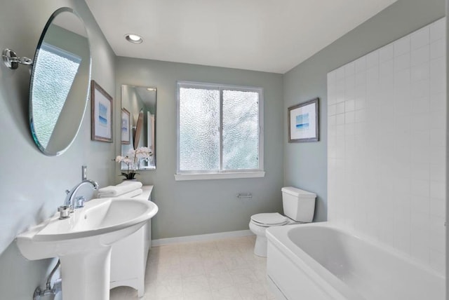 bathroom with a tub to relax in, toilet, and sink