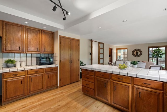 kitchen featuring tasteful backsplash, tile counters, and light hardwood / wood-style floors