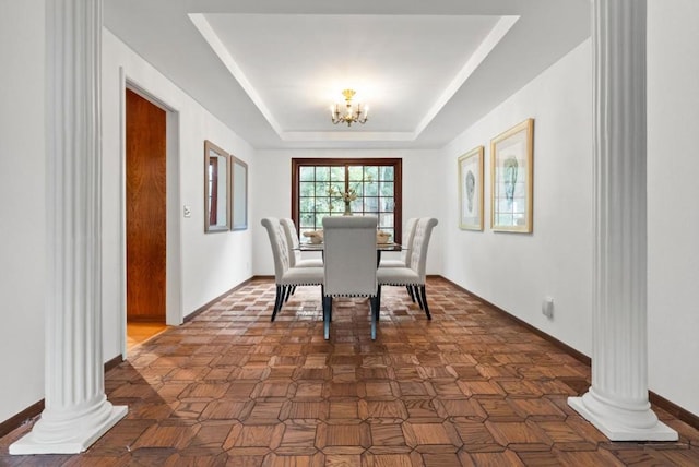 dining space featuring a notable chandelier, dark parquet floors, decorative columns, and a raised ceiling