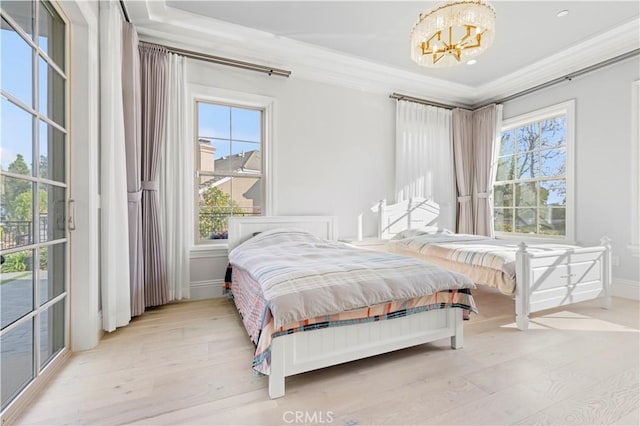 bedroom featuring light hardwood / wood-style flooring, an inviting chandelier, a tray ceiling, ornamental molding, and access to outside