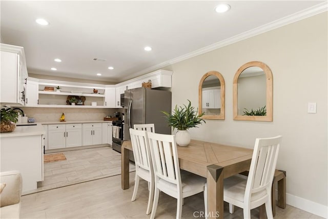 dining area featuring ornamental molding, sink, and light hardwood / wood-style flooring