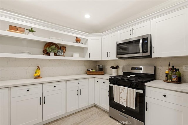 kitchen featuring white cabinetry, stainless steel appliances, light stone countertops, and backsplash