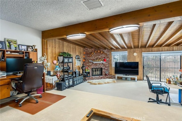 office with wooden walls, beam ceiling, a textured ceiling, and a fireplace