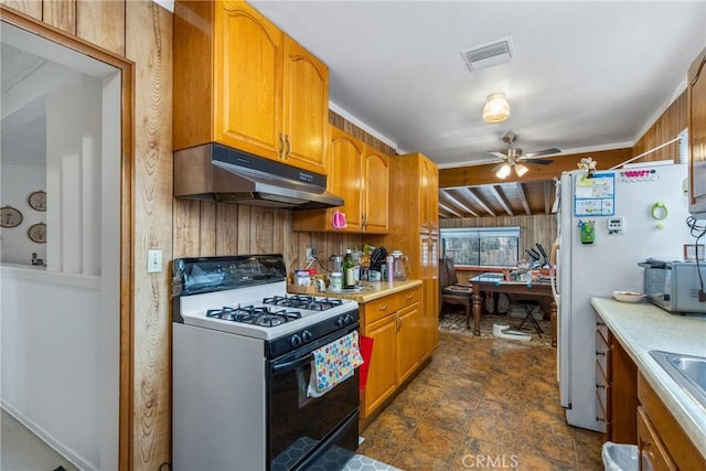 kitchen featuring ceiling fan, range with gas stovetop, and wood walls