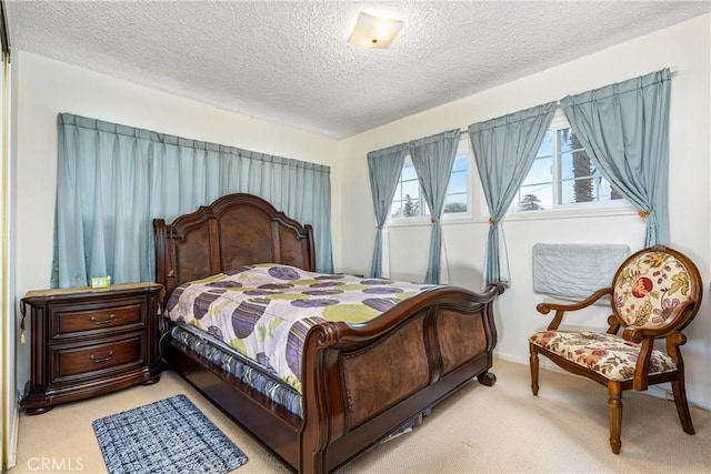 bedroom with light colored carpet and a textured ceiling