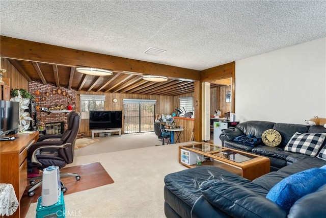 office space featuring wood walls, a brick fireplace, a textured ceiling, carpet floors, and beam ceiling