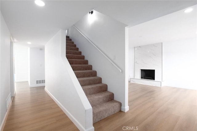 stairway featuring hardwood / wood-style floors and a high end fireplace