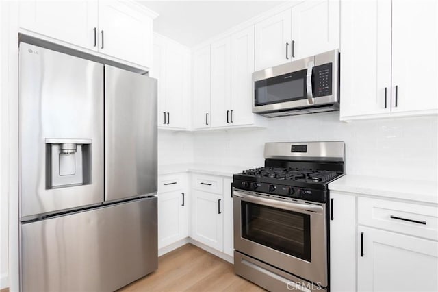 kitchen featuring white cabinetry, appliances with stainless steel finishes, backsplash, and light hardwood / wood-style floors