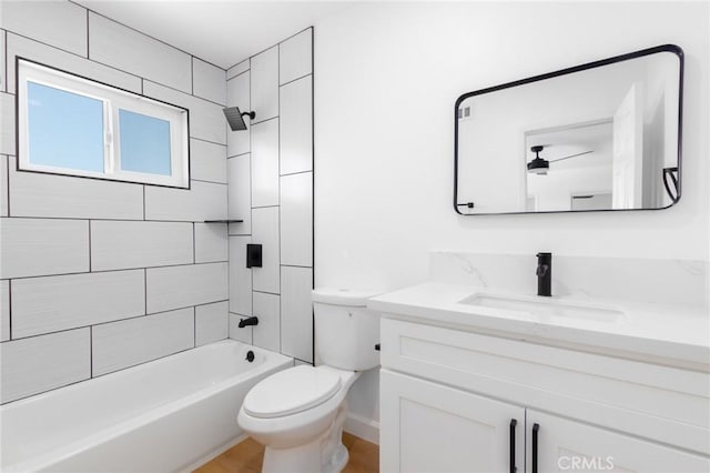 full bathroom featuring tiled shower / bath, vanity, and toilet