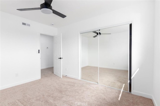 unfurnished bedroom featuring ceiling fan, light carpet, and a closet