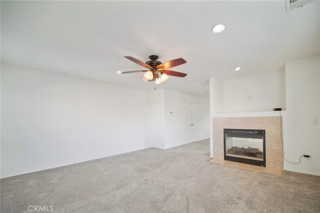 unfurnished living room with ceiling fan, light carpet, and a tile fireplace