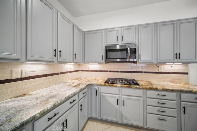 kitchen with gray cabinets, light stone counters, and black gas cooktop