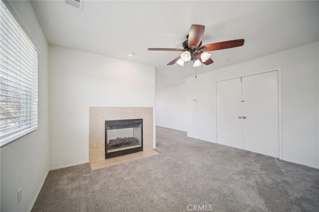 unfurnished living room featuring ceiling fan, light colored carpet, and a fireplace