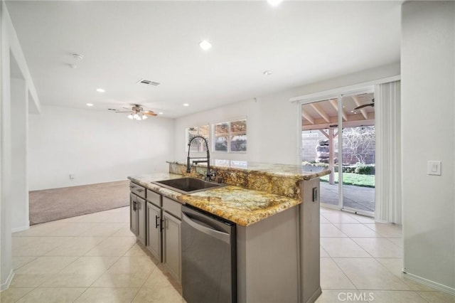 kitchen featuring sink, ceiling fan, dishwasher, light stone counters, and a center island with sink