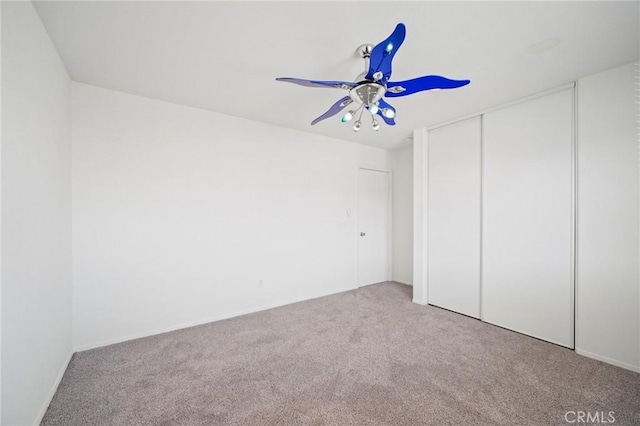 unfurnished bedroom featuring light carpet, ceiling fan, and a closet