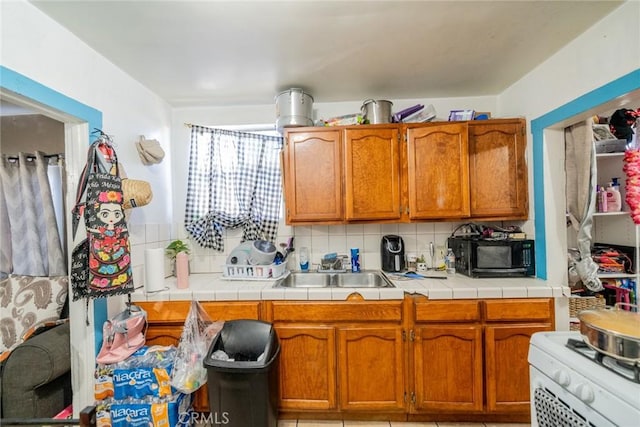 kitchen featuring sink, white gas stove, tile counters, and decorative backsplash