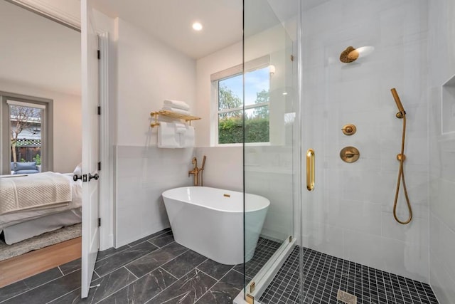 bathroom with tile walls, plenty of natural light, and shower with separate bathtub