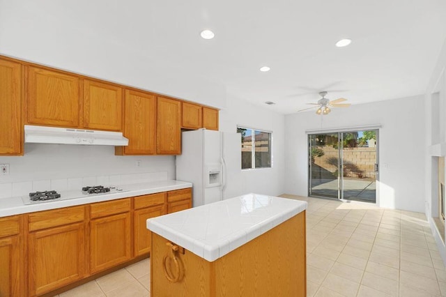 kitchen with ceiling fan, white appliances, light tile patterned flooring, and a kitchen island