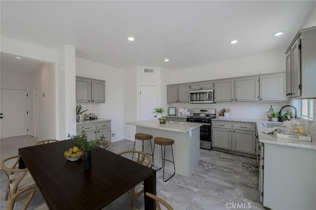 kitchen featuring appliances with stainless steel finishes, gray cabinets, sink, and a kitchen island