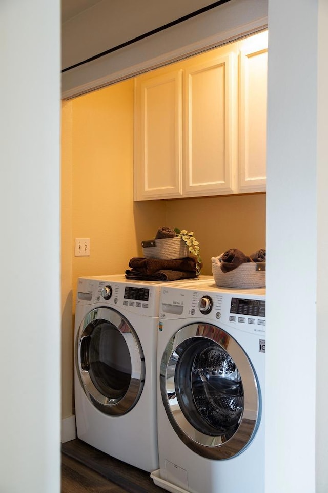 clothes washing area with cabinets, dark hardwood / wood-style flooring, and washing machine and dryer