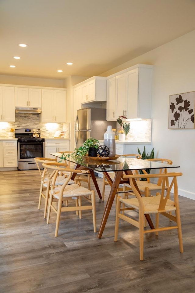 kitchen with stainless steel appliances, dark hardwood / wood-style floors, white cabinets, breakfast area, and decorative backsplash