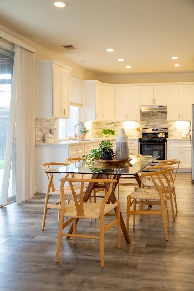 kitchen featuring sink, white cabinetry, backsplash, hardwood / wood-style floors, and stainless steel appliances