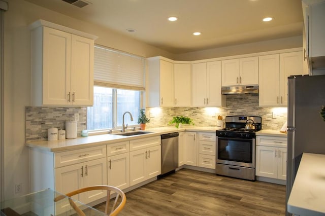 kitchen with appliances with stainless steel finishes, sink, backsplash, white cabinets, and dark hardwood / wood-style flooring