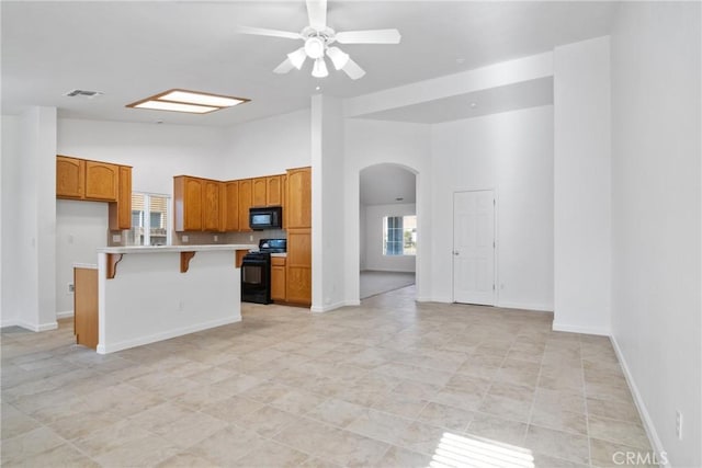 kitchen with a kitchen island, high vaulted ceiling, a kitchen breakfast bar, ceiling fan, and black appliances