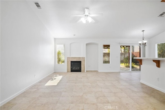 unfurnished living room featuring ceiling fan with notable chandelier and a fireplace