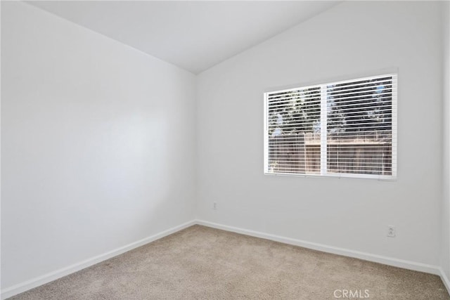 empty room featuring vaulted ceiling and light colored carpet