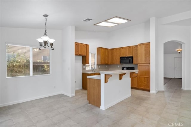 kitchen featuring pendant lighting, high vaulted ceiling, a kitchen island, decorative backsplash, and a chandelier