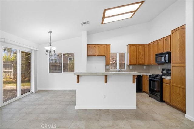 kitchen with lofted ceiling with skylight, a kitchen island, decorative light fixtures, tasteful backsplash, and black appliances