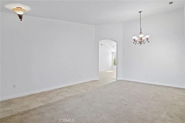 spare room with a notable chandelier and light colored carpet