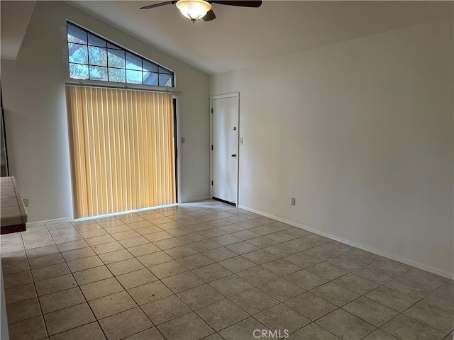 tiled empty room featuring baseboards, lofted ceiling, and a ceiling fan