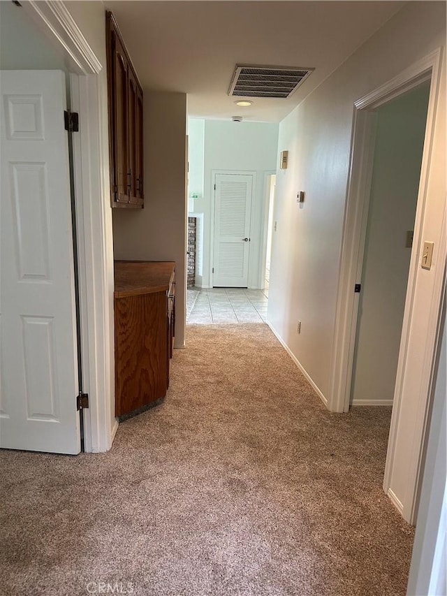 corridor with light carpet, baseboards, and visible vents