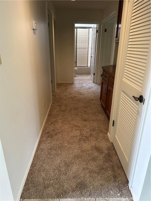 hallway with baseboards and light carpet