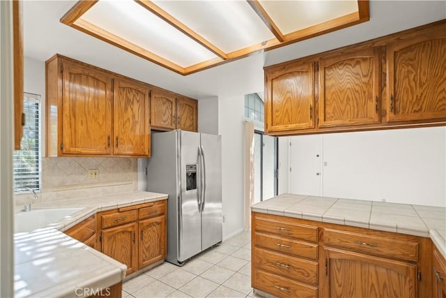 7205 Bandolero Way, Bakersfield, CA 93308 - kitchen featuring stainless steel fridge, a sink, brown cabinetry, light tile patterned flooring, and backsplash