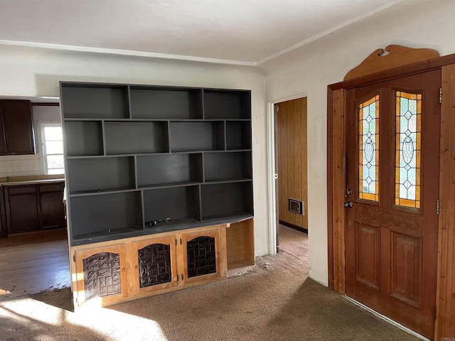 foyer entrance with dark carpet and ornamental molding