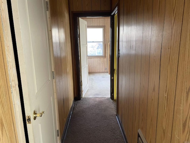 hall featuring wooden walls and dark carpet