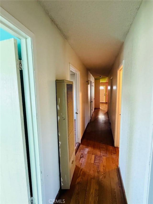 hall featuring dark wood-style flooring, a heating unit, and a textured ceiling