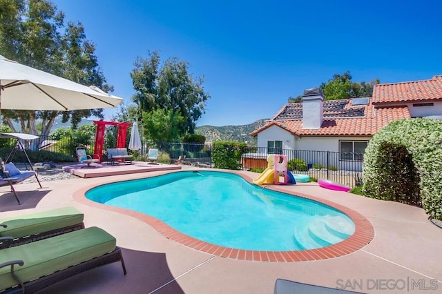 view of swimming pool with a mountain view, a patio, and a playground