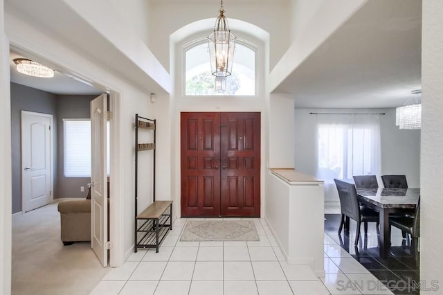 tiled foyer entrance with a towering ceiling and a notable chandelier